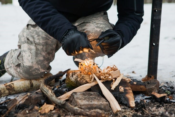 man starting fire with fire starter